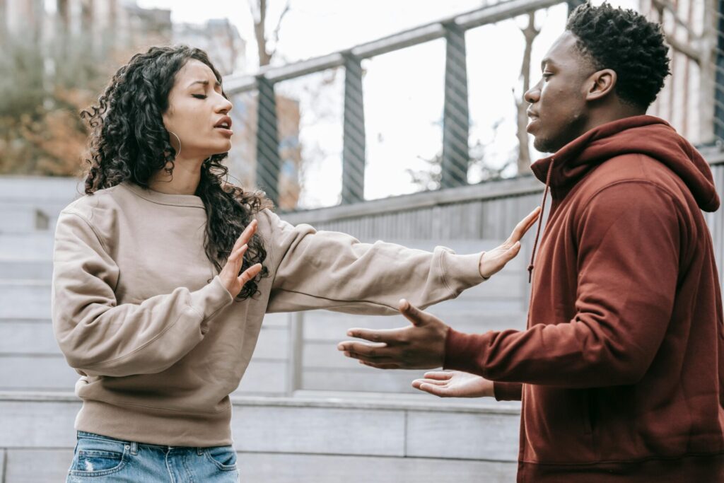 A couple engaged in a heated argument outside on city steps, conveying tension.